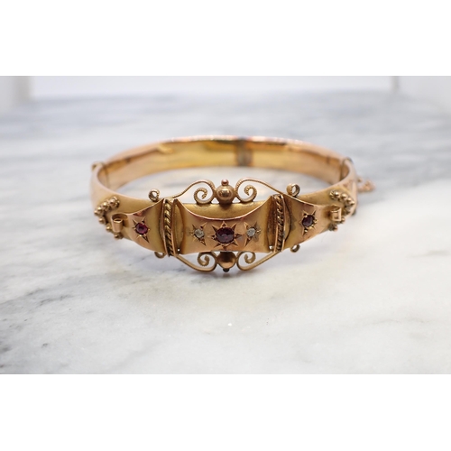 172 - An Edwardian 9ct gold hinged Bangle the front with ornate design set three rubies and two rose-cut d... 