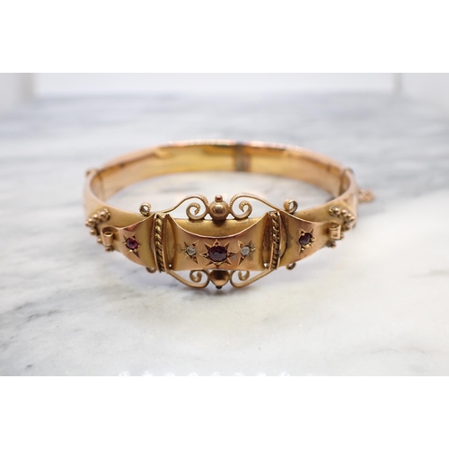172 - An Edwardian 9ct gold hinged Bangle the front with ornate design set three rubies and two rose-cut d... 