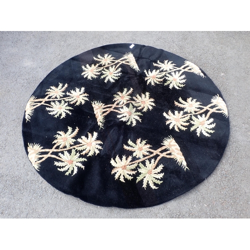 56 - A modern circular black ground rug decorated with tree designs