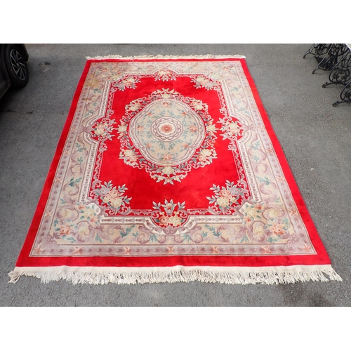 57 - A modern red ground rug with multi boarders of floral and leafage design with a central floral motif