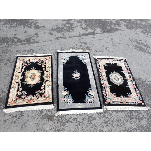 713 - Three modern black ground Rugs with floral borders and central floral motifs, largest measuring 6ft ... 