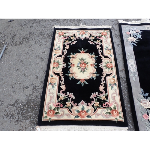 713 - Three modern black ground Rugs with floral borders and central floral motifs, largest measuring 6ft ... 