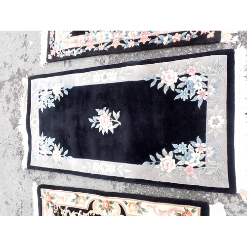 713 - Three modern black ground Rugs with floral borders and central floral motifs, largest measuring 6ft ... 