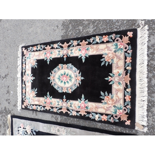 713 - Three modern black ground Rugs with floral borders and central floral motifs, largest measuring 6ft ... 