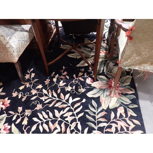 55 - A large modern black ground rug with a green leafage patterned border, 13ft 2in x 9ft 2in