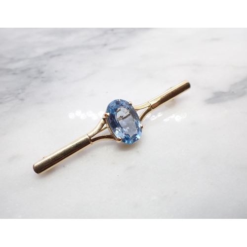 142 - A 9ct gold Bar Brooch claw-set oval-cut blue synthetic spinel, approx 58mm long, approx 4.90gms