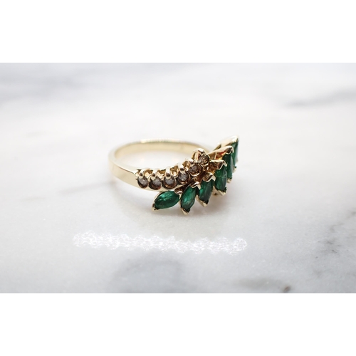 162 - An Emerald and Diamond Ring the crossover-mount set seven marquise-cut emeralds between rows of bril... 