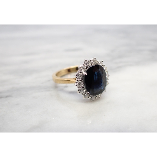 169 - A Sapphire and Diamond Cluster Ring claw-set oval-cut sapphire, 3.28cts, within a frame of brilliant... 