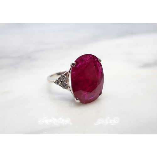 182 - A Ruby and Diamond Ring claw-set oval-cut ruby, 11.43cts, between trios of brilliant-cut diamonds in... 