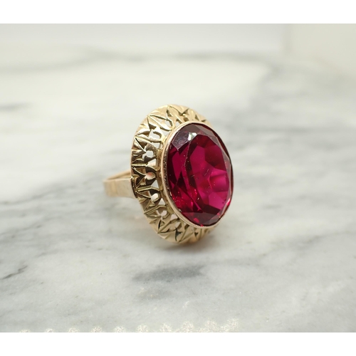 192 - A synthetic Ruby Dress Ring set oval-cut stone in pierced frame, tests as 14ct, ring size Q, approx ... 