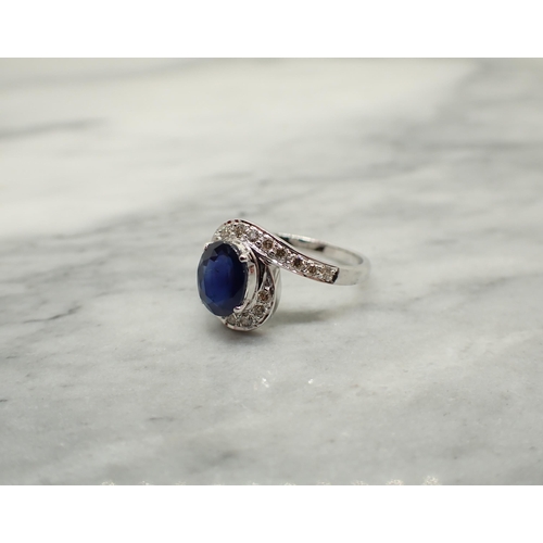 205 - A Sapphire and Diamond Cluster Ring claw-set oval-cut sapphire within a frame of pavé-set brilliant-... 