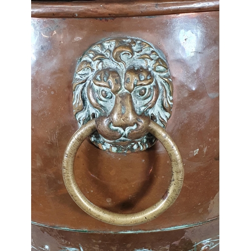 365 - An antique copper Log Cauldron with lion mask ring handles, raised on paw supports, 15