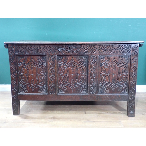 523 - An antique oak Coffer with moulded hinged cover above a three panelled carved front, 4ft 3in W