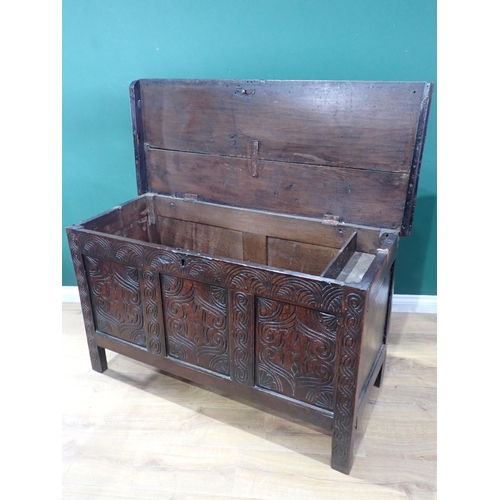 523 - An antique oak Coffer with moulded hinged cover above a three panelled carved front, 4ft 3in W