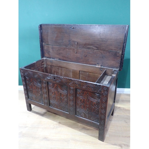 523 - An antique oak Coffer with moulded hinged cover above a three panelled carved front, 4ft 3in W