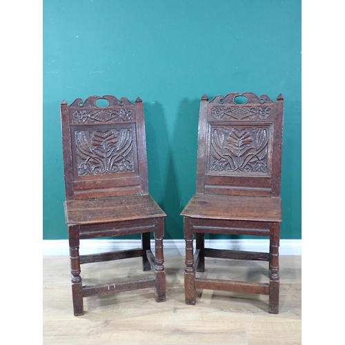 525 - A pair of 17th Century oak Hall Chairs with pierced shaped crests above foliate carved panel backs, ... 