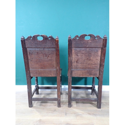 525 - A pair of 17th Century oak Hall Chairs with pierced shaped crests above foliate carved panel backs, ... 