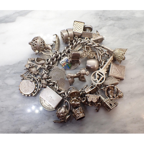 169 - A silver curb-link Bracelet with numerous silver and white metal charms, approx 160gms all in