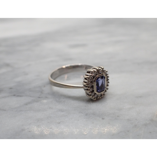 175 - A Tanzanite and Diamond Cluster Ring rubover-set step-cut tanzanite with a frame of brilliant-cut di... 