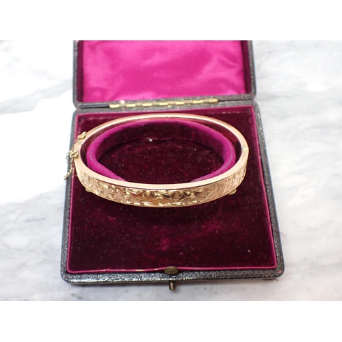 186 - A 9ct gold hinged Bangle, the front engraved ivy, approx 12gms, in fitted case