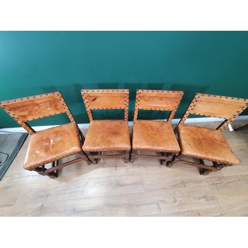 34 - A set of four leather upholstered and oak Dining Chairs with studded detail and raised on squared an... 