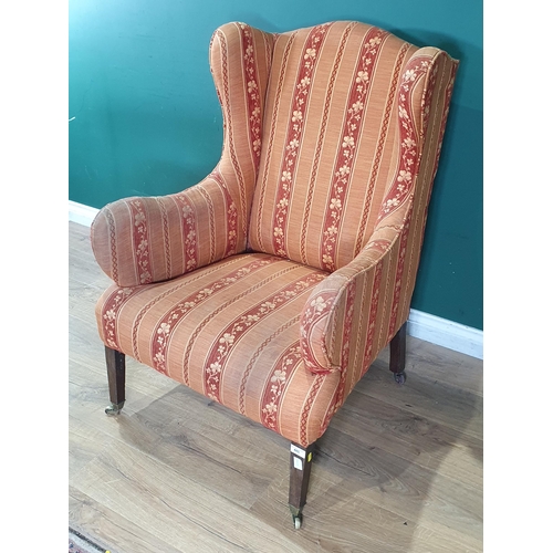 485 - A 19th Century wingback Armchair with striped upholstery and raised on squared supports and casters