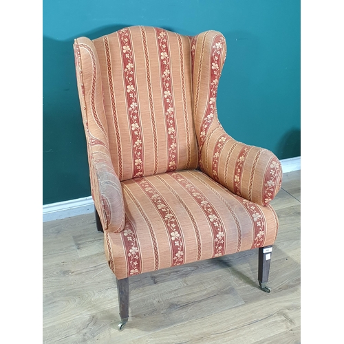 485 - A 19th Century wingback Armchair with striped upholstery and raised on squared supports and casters