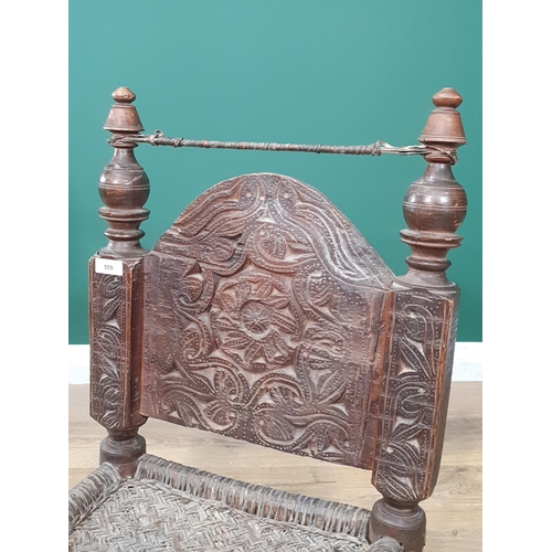 509 - An Indian carved Low pidha Chair with arched back, woven seat on turned supports