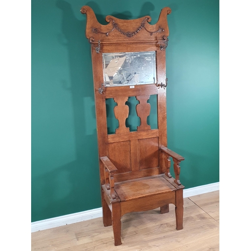 546 - An oak Hall Bench with shaped top above four coat hooks, flanking a central mirror with hinged seat.