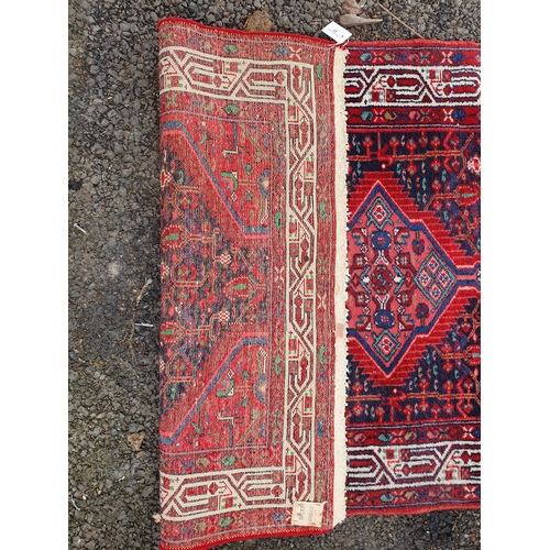 63 - A bordered Persian Rug with central medallion on a pink ground, the surround with red patch on a blu... 