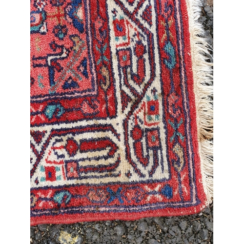 63 - A bordered Persian Rug with central medallion on a pink ground, the surround with red patch on a blu... 