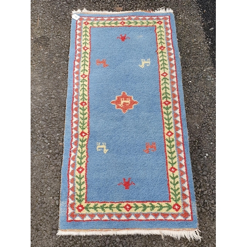 852 - A small light blue ground Rug with animal motifs