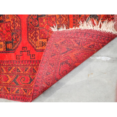 89 - A bordered Afghan Rug with three large guls on a red ground, 5ft 3in 3ft 6in