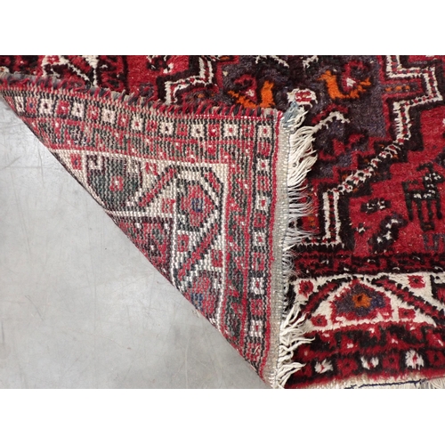 92 - A bordered Eastern Rug with triple lozenge on a red ground, 5ft 2in x 3ft 4in