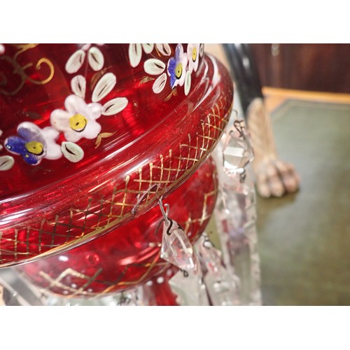 96 - A pair of Victorian ruby glass Table Lustres painted floral swags and gilt above triangular prism dr... 