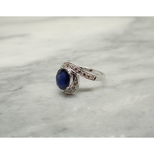 173 - A Sapphire and Diamond Cluster Ring claw-set oval-cut sapphire within a frame of pavé-set brilliant-... 