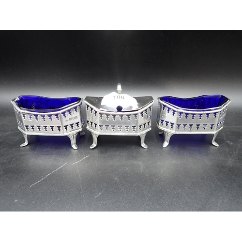 108 - A George V silver large three piece Condiment Set of pierced octagonal form with blue glass liners, ... 