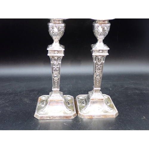 135 - A pair of Edward VII silver Candlesticks with ribbons, swags, ram's head masks on beaded square base... 