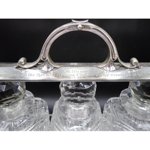 136 - A plated mounted Tantalus with presentation inscription, fitted three square cut glass Decanters and... 