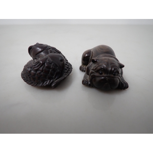 148 - A Japanese hardwood Netsuke in the form of a bulldog and another of two Carp