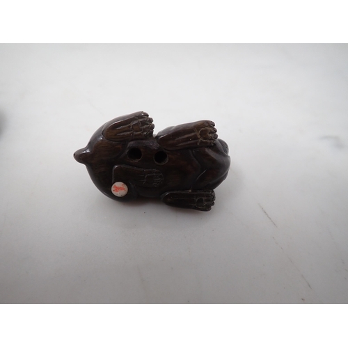 148 - A Japanese hardwood Netsuke in the form of a bulldog and another of two Carp