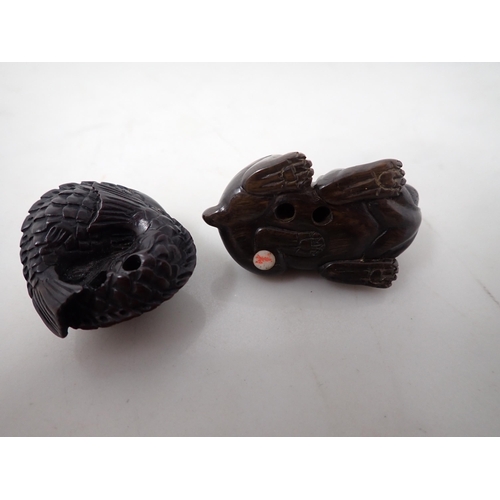 148 - A Japanese hardwood Netsuke in the form of a bulldog and another of two Carp