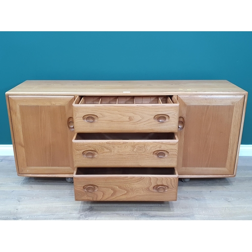 2 - An Ercol Sideboard fitted three drawers flanked by panelled cupboard doors, raised on castors, 5ft 2... 