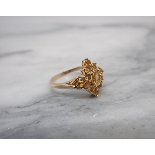 207 - A Citrine Cluster Ring claw-set oval-cut stone within smaller round stones in 14ct gold, ring size P