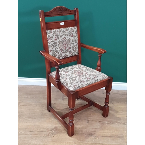 31 - An oak Elbow Chair with carved and arched back with coat of arms and floral upholstery on turned and... 