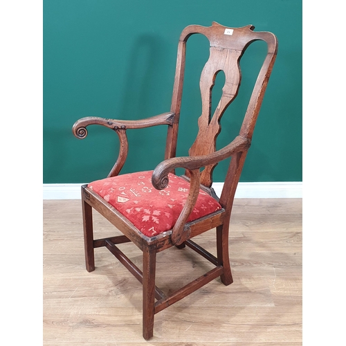 474 - An antique oak and elm pierced splat back Country Elbow Chair with scrolled arms, red upholstered dr... 