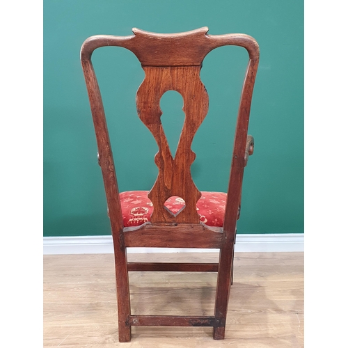 474 - An antique oak and elm pierced splat back Country Elbow Chair with scrolled arms, red upholstered dr... 