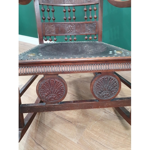 609 - An Arts and Crafts bobbin back Rocking Chair in the manner of Carlo Bugatti with tooled leather work... 