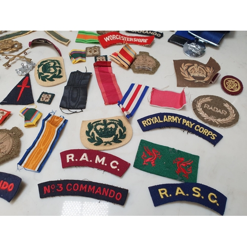 225 - A bag of Military Badges and other items including SAS Belt, Cloth Badges, Royal Engineers Cap Badge... 