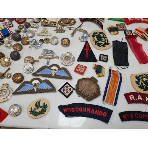 225 - A bag of Military Badges and other items including SAS Belt, Cloth Badges, Royal Engineers Cap Badge... 